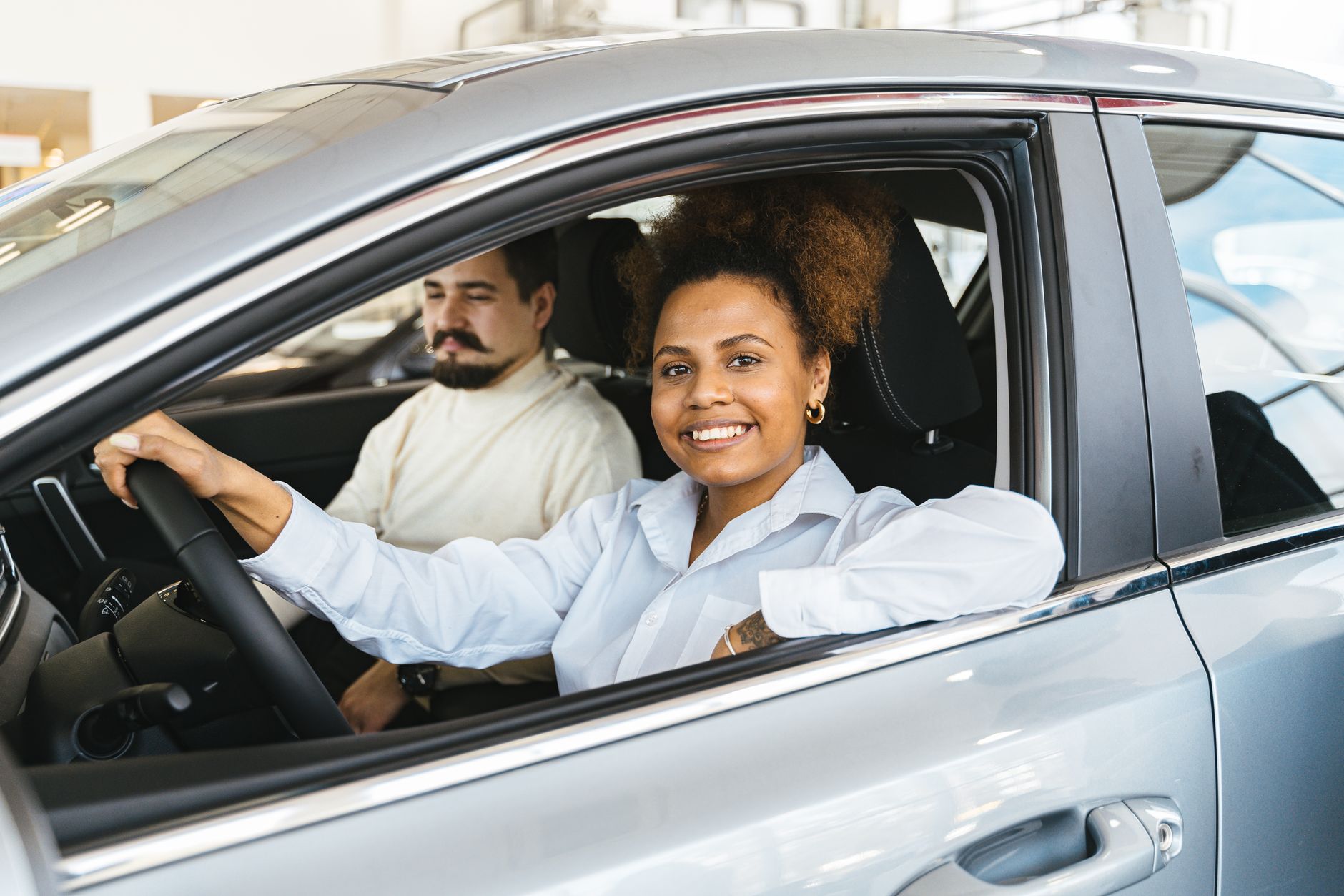 Happy interracial couple sitting in a new car showroom, enjoying their recent purchase.