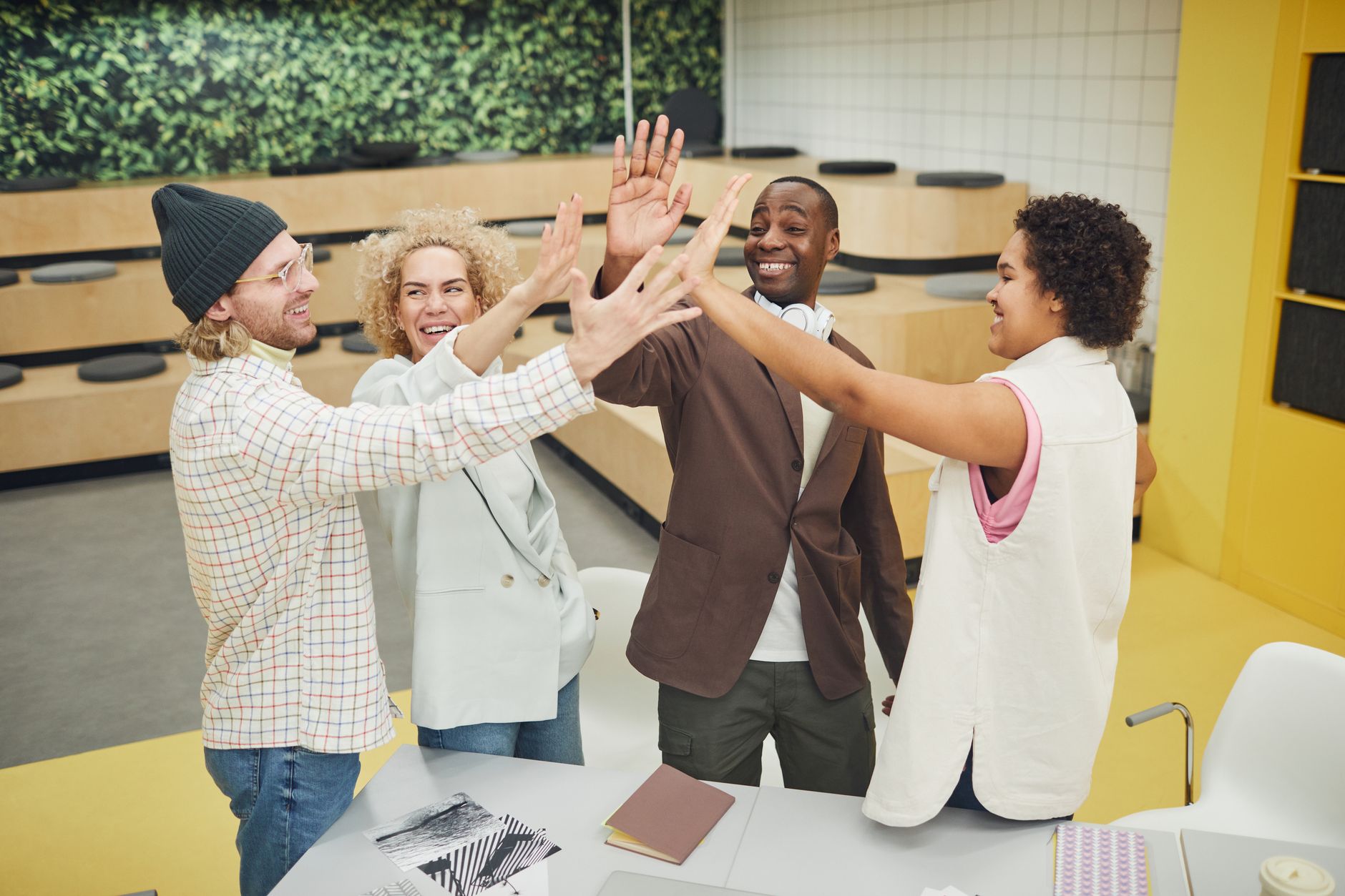 A group of diverse colleagues in business attire celebrating with a high five indoors.